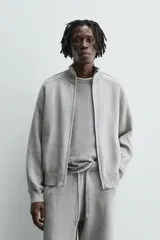 Chaqueta de punto compacto con mezcla de algodón, corte relajado, cuello subido, manga larga, bolsillos laterales de vivo y cierre frontal con cremallera.
