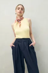 Pantalón color crema de corte ancho, con cintura alta y pinzas delanteras.