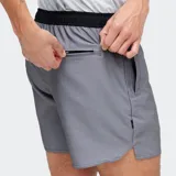 Short deportivo de hombre color gris, con cintura elástica negra y cordón de ajuste blanco. Presenta un corte por encima de la rodilla y bolsillos laterales.