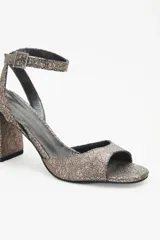 Sandalias de cuero vacuno color peltre con textura craquelada, tira delantera y tobillera con hebilla metálica, forro de cuero caprino y suela de cuero reconstituido con taco geométrico.