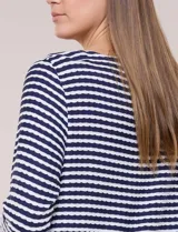 Blusa de tejido de punto acanalado con diseño de rayas horizontales en color azul marino y blanco. Presenta cuello bote, mangas tres cuartos y ruedo curvo.