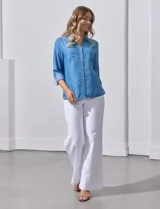 Camisa celeste de lyocell, con cuello a la base, escote en V y abertura central con botones. Tiene bolsillos aplicados en la parte delantera y mangas 3/4 regulables con presilla y botón.