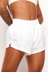 Short deportivo de color blanco con cintura elástica fruncida, aberturas laterales en el dobladillo y forro interno anatómico.