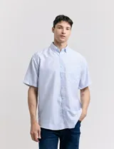 Camisa blanca con estampado de micro lunares celestes, de corte clásico, manga corta, cuello abotonado y bolsillo en el pecho.