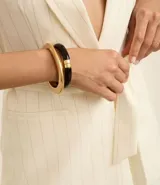 Kit de dos brazaletes rígidos, uno de color negro y otro de color dorado, con diseño minimalista y estructura articulada.