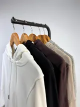 Buzo tipo canguro de corte oversize, color marrón oscuro, con capucha y cordones ajustables. Presenta costuras verticales decorativas, bolsillos laterales y ruedo con terminación desflecada.