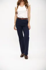 Pantalón de vestir ancho color azul marino, de tiro alto y corte recto, con pliegues frontales y cinturón marrón.