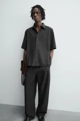 Pantalón de corte relajado confeccionado en tejido fluido con mezcla de lyocell. Presenta cintura elástica ajustable con cordón, bolsillos laterales y un bolsillo trasero de vivo con botón.