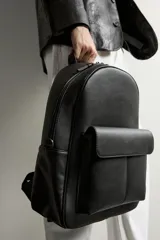 Mochila marrón oscuro con acabado abatanado, compartimento principal con cierre, bolsillo frontal con solapa y asa de mano.