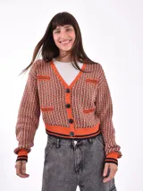 Saco tejido de punto grueso, color negro, con cuello en V y botones frontales. Presenta detalles de punto en contraste en los bolsillos y puños.