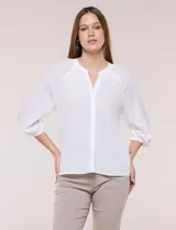 Blusa de gasa color blanco, de corte holgado, con cuello a la base, escote en V y cartera con botones. Cuenta con fruncidos en el cuello y hombros, mangas tres cuartos abullonadas con puño elástico y ruedo redondeado.