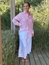 Camisa celeste a rayas verticales blancas, de corte holgado, manga larga y cuello camisero.