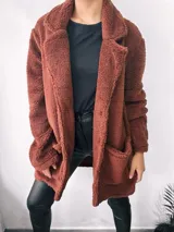 Saco largo color marrón chocolate, estilo teddy, con solapas y bolsillos laterales. Cierre frontal con botones. Talle único oversize.