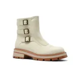 Bota de caña media color beige, confeccionada en material tipo gamuza, con suela track de goma en tono terracota y tres correas laterales con hebillas metálicas decorativas.