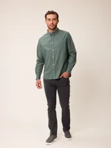 Camisa de manga larga en color azul, confeccionada en algodón con técnica de teñido garment dye. Presenta cuello abotonado, cierre frontal con botones y un bolsillo en el pecho con detalle bordado.