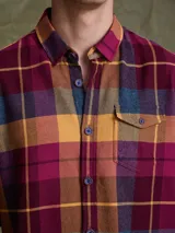 Camisa de manga larga en color azul noche con un patrón de cuadros finos en tonos rojos y verdes. Presenta cuello clásico, cierre frontal con botones y un bolsillo en el pecho con solapa.