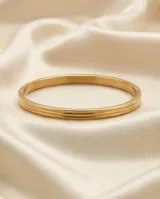 Pulsera tipo esclava rígida de acero con baño de oro, con diseño de líneas paralelas en relieve.