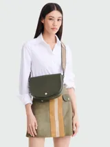 Cartera tipo crossbody Longchamp modelo Epure, de diseño semicircular en color verde oliva. Presenta una solapa frontal con cierre de broche metálico dorado y correa ajustable de lona en tono beige.
