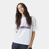 Camiseta blanca de corte "boxy fit" con estampado frontal que dice "emestudios" en azul con detalles rojos, y debajo "EXCLUSIVE PIECES SELECTED WITH CARE / MADRID".