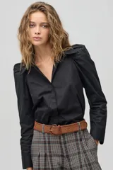Camisa negra de algodón con cuello clásico, mangas largas con puños y hombros fruncidos que aportan volumen.
