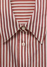 Camisa de corte recto con diseño de rayas verticales en tonos terracota y blanco. Presenta cuello camisero clásico, cierre frontal con botones y mangas largas con puños abotonados.