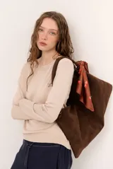 Sweater de punto color beige, de cuello redondo y manga larga, con detalle de pequeño bordado en el pecho.