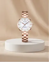 Reloj analógico de mujer con caja redonda y malla de eslabones en tono oro rosa. Presenta una esfera minimalista con índices lineales y movimiento de cuarzo japonés.
