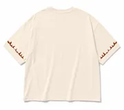 Remera oversize color beige, con cuello redondo y mangas cortas. Presenta un pequeño estampado frontal con la inscripción "Lrola Since 2020" y detalles de llamas marrones en los dobladillos de las mangas.