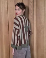 Buzo de punto con diseño de rayas verticales en tonos tostado y beige, con una estrella grande en la espalda y terminaciones en color verde oliva. Presenta un corte holgado y mangas anchas.