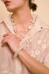 Brazalete rígido cubierto íntegramente con perlas pequeñas y abalorios dorados.
