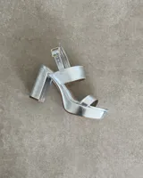 Sandalias plateadas de plataforma con tacón cuadrado, tira ancha sobre los dedos y tobillera con hebilla dorada.