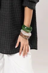 Pulsera rígida de resina marrón con tachas metálicas plateadas distribuidas a lo largo de toda la pieza.