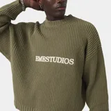 Sweater de punto grueso verde militar, con cuello redondo, puños y bajo de canalé, y logotipo bordado de EME Studios en el pecho. Presenta silueta holgada y cuadrada.