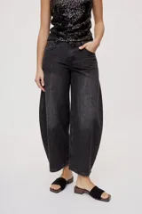 Jean de tiro medio y corte barrel con pierna amplia y ligeramente curva, estilo de cinco bolsillos en denim negro lavado.