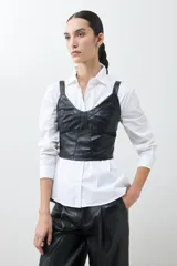 Top negro de cuero sintético con breteles finos y corte ajustado.