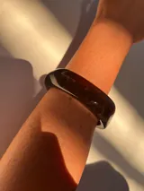 Brazalete rígido de acrílico color marrón oscuro con forma irregular.