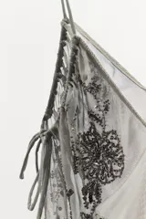 Top de tul con escote en pico y tirantes finos. Presenta bordados florales con aplicación de lentejuelas y laterales ajustables mediante lazadas.