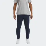 Pantalón deportivo Reebok Identity para hombre, color azul marino, confeccionado en tejido polar de algodón y poliéster reciclado. Presenta un ajuste versátil, cintura elástica con cordón y puños elásticos en los tobillos. Cuenta con un pequeño logotipo Reebok bordado.