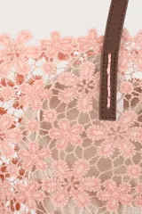 Bolso tipo tote de encaje rosa claro con diseño de flores, asas marrones y neceser interior beige.