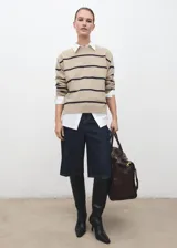 Jersey de punto de corte recto con diseño de rayas horizontales oscuras sobre fondo beige. Presenta cuello redondo, manga larga y tejido de punto medio.