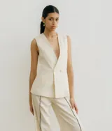 Chaleco sastrero blanco de lino, con cuello en V profundo y cierre cruzado con botones.