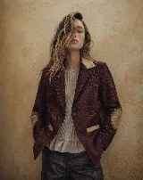 Blazer de paño de lana color bordó con cuello, vivos en bolsillos y parches en los codos de cuero en tono beige. Presenta un diseño de calce relajado con cierre frontal de un botón.