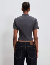 Top de sastrería color gris grafito, con cuello alto, manga corta y silueta entallada. Presenta un diseño con doble hilera de botones decorativos frontales y largo a la cintura.