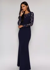 Vestido largo de fiesta color azul marino, con mangas largas de encaje y escote redondo. Presenta un diseño entallado que se ensancha suavemente hacia el ruedo.