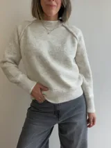 Sweater de tejido suave en color beige jaspeado, con cuello redondo, mangas largas con puños acanalados y diseño de corte holgado.