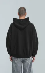 Hoodie oversize de algodón, color negro, con capucha forrada, bolsillo frontal tipo canguro y bolsillo con cierre en la manga estilo bomber.