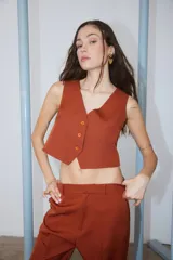 Chaleco color ladrillo de tela sastrera con forrería de poplín de algodón a tono, escote en V y cierre frontal con botones.