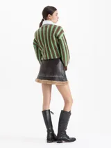Minifalda de cuero ovino color marrón oscuro con bordados florales en tonos amarillos y verdes. Presenta un ruedo con detalle de piel sintética afelpada y una estructura definida.