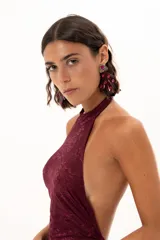 Vestido largo de encaje color bordó, con escote halter y diseño ajustado en el torso que se extiende hasta la cintura, donde continúa con una falda larga de encaje transparente.