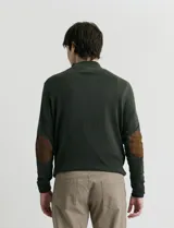Sweater de punto color verde oliva, con cuello alto y medio cierre frontal. Presenta coderas en símil nappa y puños acanalados.